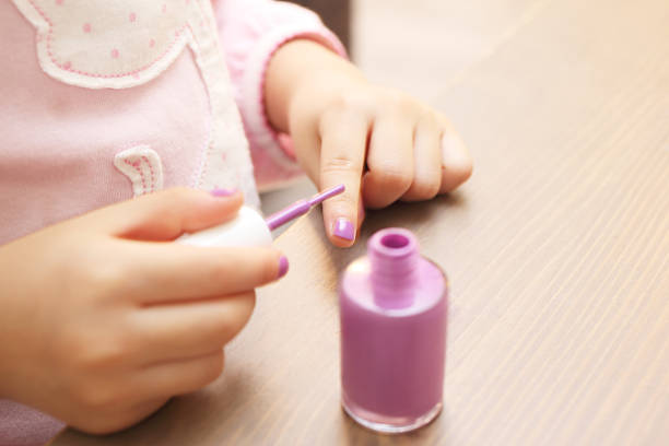 Close-up of a little girl putting on fingernail polish.