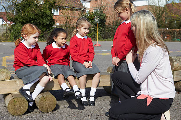 istock Teacher holding a little girl while talking to three others 181079484