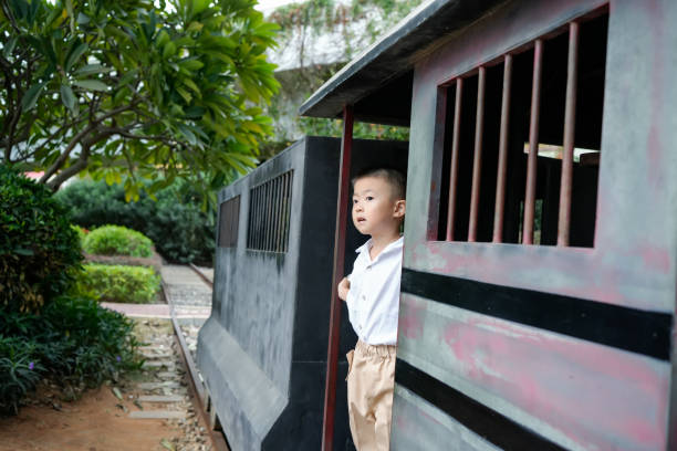 The boy stood on an old-fashioned train looking out