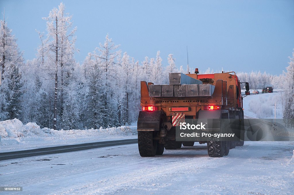 Winter. Western Siberia. Winter  road. On the way, a truck drives slowly with building materials (concrete piles). Bush Stock Photo