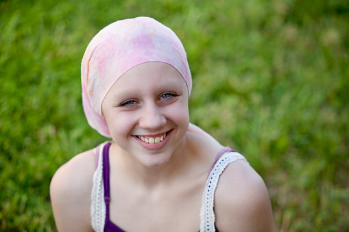 Happy young girl with cancer smiling in Head Scarf