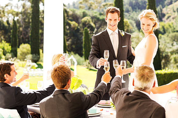 istock Bride and Groom Toasting Champagne Flutes With Guests During Reception 181082604