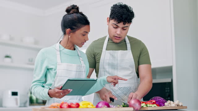 Cutting vegetables, tablet and couple cooking in kitchen, healthy food tutorial and recipe. Tech, man and woman cook together, knife on chopping board and vegan meal for diet, nutrition or wellness