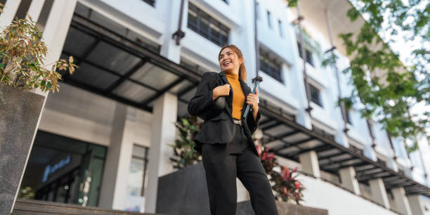 geschäftsfrau, die erfolgreich im freien zur arbeit geht. schöne frau, die mit kaffee zur arbeit geht, in der nähe des bürogebäudes spazieren geht - non urban scene fotos stock-fotos und bilder