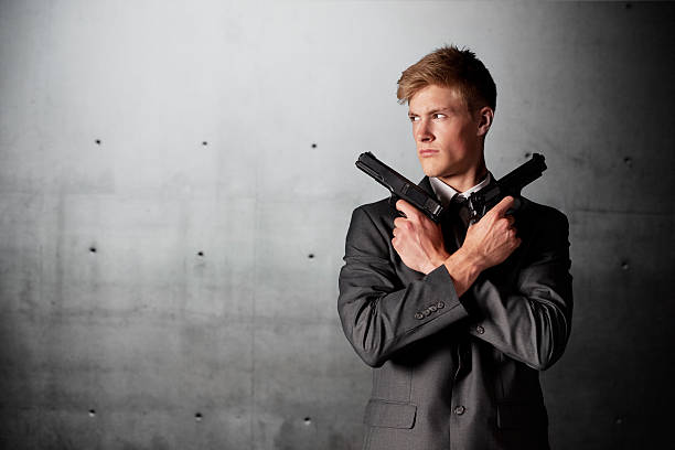 hübscher junger geschäftsmann halten handguns - bodyguard holding gun 20s stock-fotos und bilder