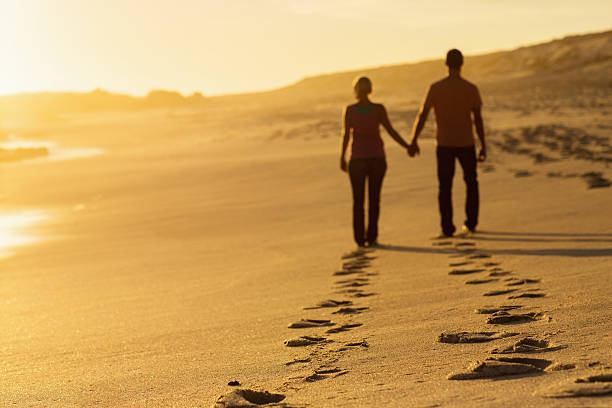 istock Couple Walking On Beach Leaving Behind Track Of Footprints 181086270
