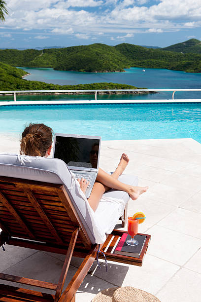 istock businesswoman working on laptop while sunbathing at the pool 181086644