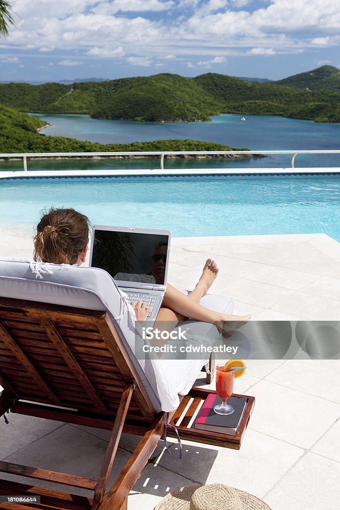 businesswoman working on laptop while sunbathing at the pool businesswoman working on laptop while sunbathing at the pool in the Caribbean Laptop Stock Photo