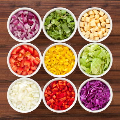 Nine bowls containing variety of chopped vegetables