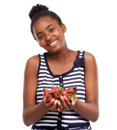 Studio portrait of a happy young african american girl holding a pile of strawberries isolated on white