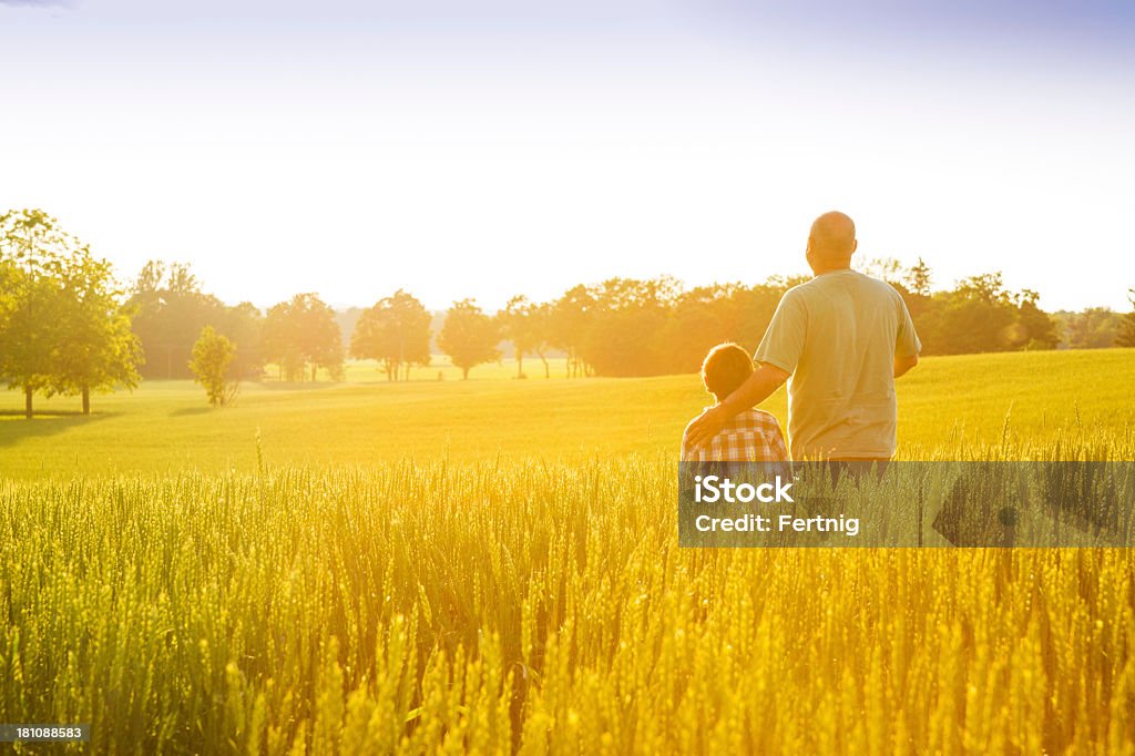 Landwirt mit seinem Sohn im Sonnenuntergang - Lizenzfrei Bauernberuf Stock-Foto