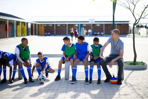 istock Coach sitting on bench talking to young soccer players before practice 1810886051