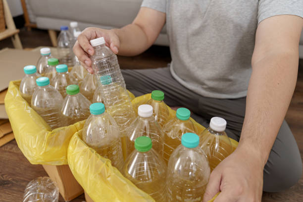 istock Home recycle eco green zero concept Man throwing empty plastic bottle in recycling bin with yellow garbage bags at home 1810892228