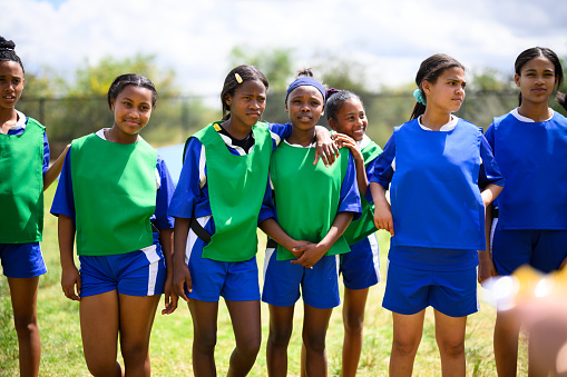 Schoolgirls playing soccer in teams on grass outside rural school