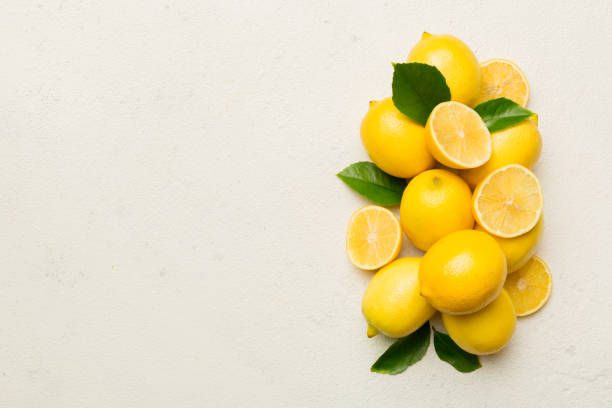 istock Many fresh ripe lemons with green leaves on colored background, top view, space for text 1810893300