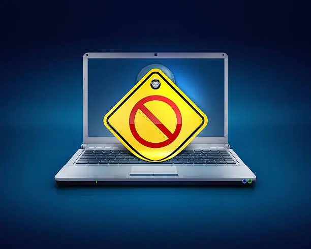 computer laptop screen on a blue background with sticky note showing the traffic sign of no entry for no access networks or blocked website etc.. Concept of internet security, maleware and antivirus protections on a PC.