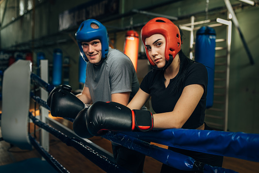 Female and male Caucasian boxer lean on the ring and look at the camera