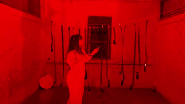 Young woman looking camera film in darkroom with red light