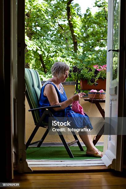 Senior Mujer Sencuentra En El Balcón Y Knits Un Pullover Foto de stock y más banco de imágenes de 70-79 años