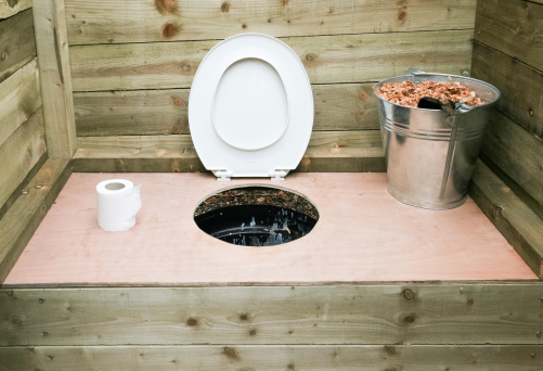 A home made compost toilet, made from board and plywood. With a hole cut in the plywood, leading to a black bucket.