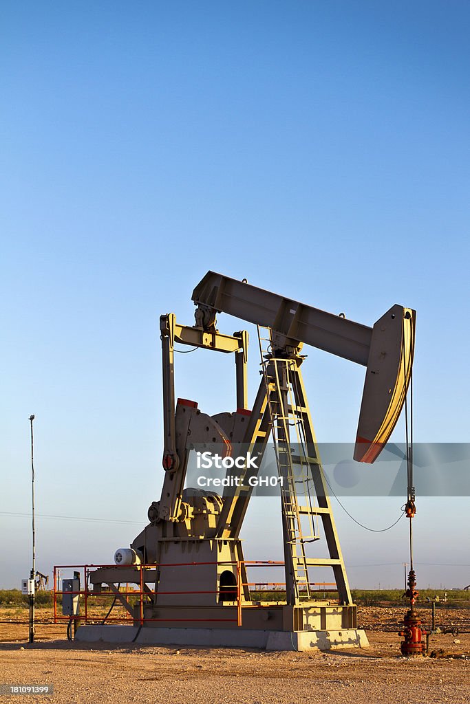 Oil Rig Pump Jack Modern oil rig pump jack shot in early morning light with other oilfield equipment in background Agricultural Field Stock Photo