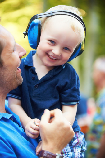 Cute little boy lifted up by his father while wearing noise-canceling headphones