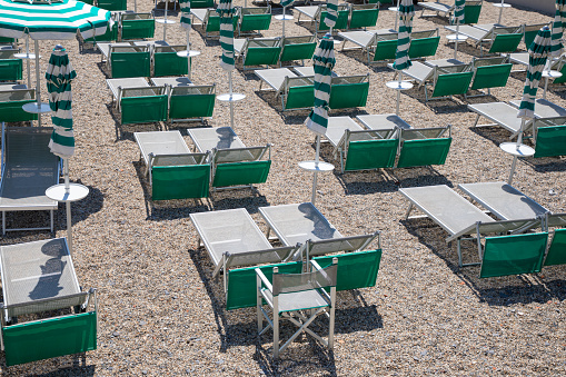 beach umbrellas green and recliner chairs bed seat in a private beach in italian coast