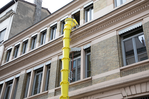 plastic slide chute yellow for rubble debris removal on building facade renewal construction site in city street