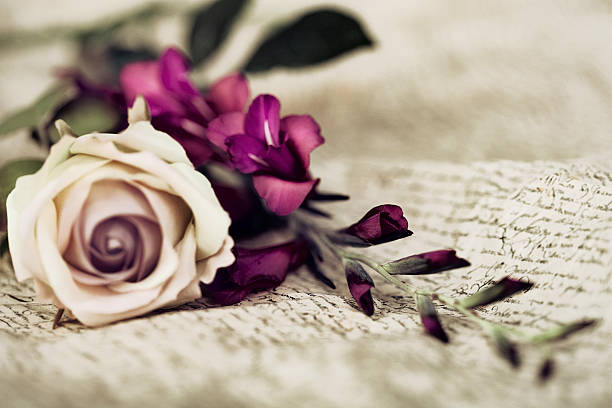 White rose next to purple flowers over a calligraphy cloth