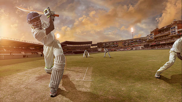 Cricket Batsman Hits A Six Batsman just after hitting ball in professional cricket match in full stadium at sunset during summer cricket stock pictures, royalty-free photos & images
