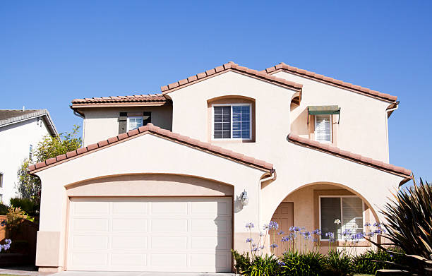 istock Exterior of a stucco home with a blue sky behind it 181095078
