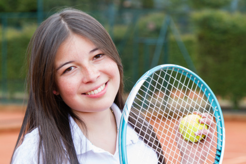 Portrait of a happy tennis player holding a racket and ball