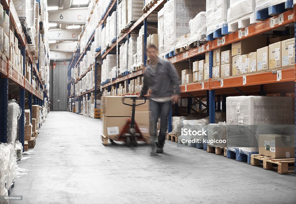 Rushing to get the order ready A young man using a pallet truck to transport boxes in a storehouse Warehouse Worker Stock Photo