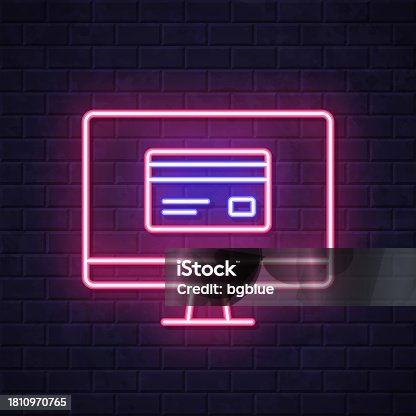 istock Desktop computer with credit card. Glowing neon icon on brick wall background 1810970765
