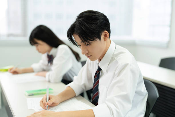 Adolescentes asiáticos con uniformes de escuela secundaria estudiando en clase - foto de stock