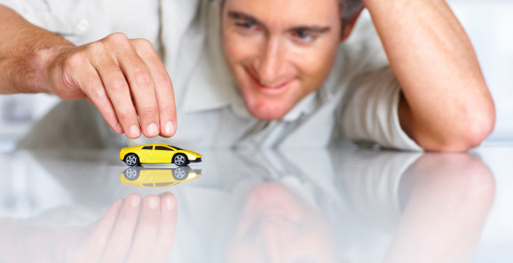 Mature man playing with a toy sportscar