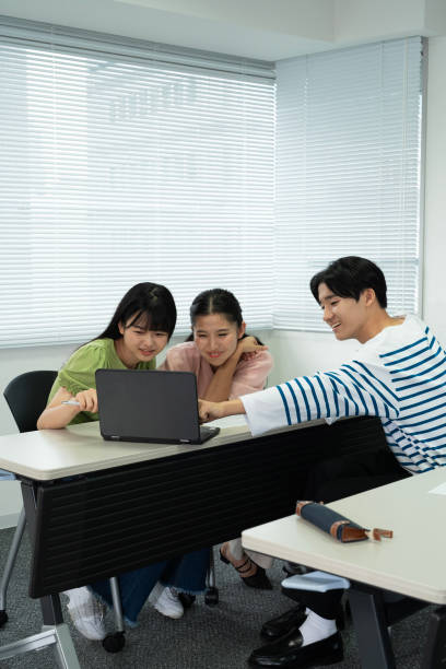 Asian teenagers using a laptop in discussion