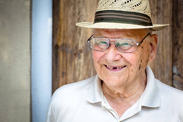 portrait of a laughing senior man with a straw hat roguish laughing senior man with glasses and a straw hat gap toothed photos stock pictures, royalty-free photos & images