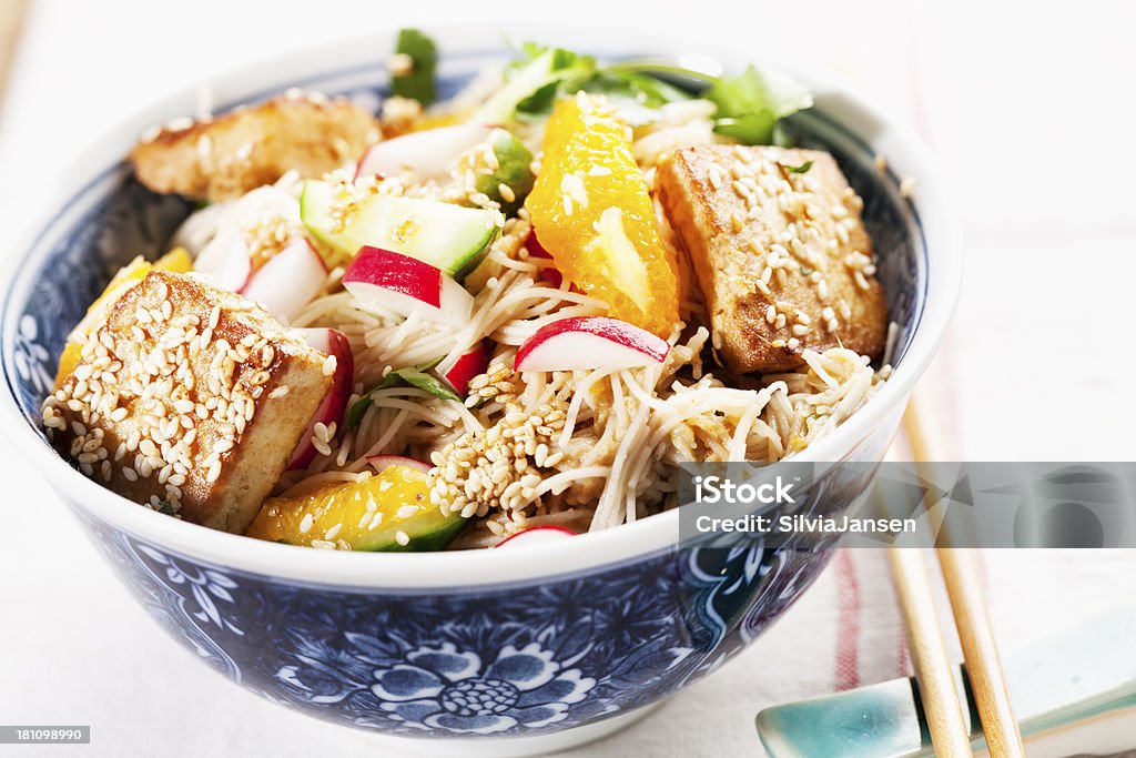 rice noodles cucumber radish orange salad with tofu salad made of rice noodles, radish, cucumber and orange slices, with fried tofe slices covered with sesame seeds Beige Stock Photo