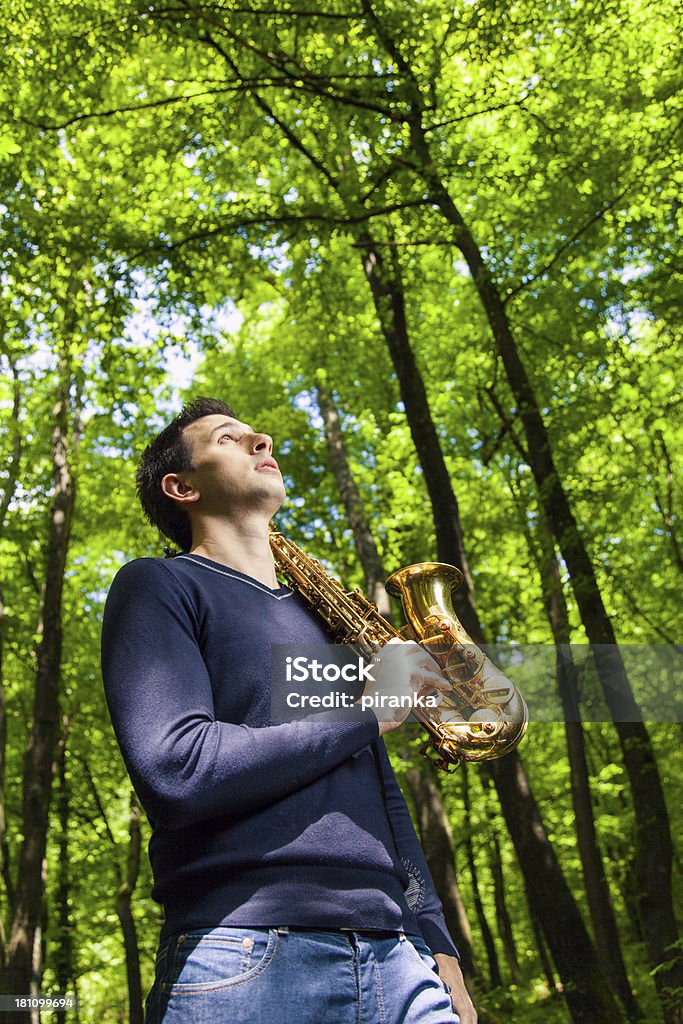 Man with saxophone looking up Man with saxophone standing in the woods, looking up Saxophonist Stock Photo