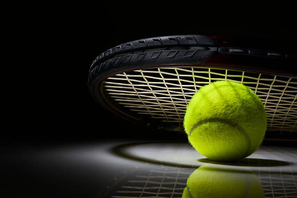 Tennis racket and ball on dark background stock photo