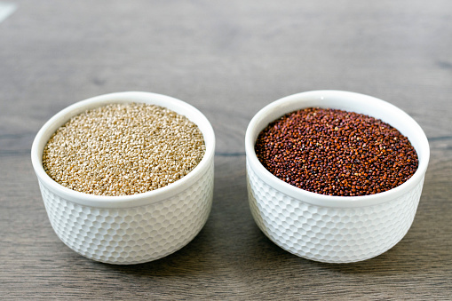 Red and white quinoa on the two white plates on the wooden background. Healthy food and nutrition concept. Safe, ecological, and healthy products.