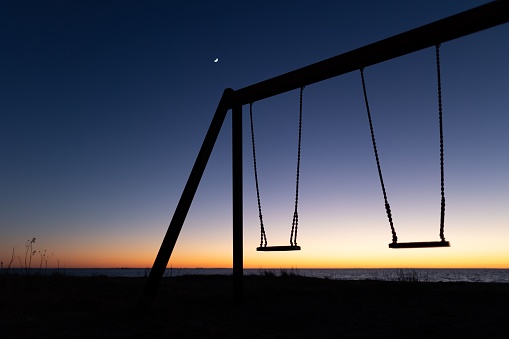 The two swings against a backdrop of a beautiful sky with vibrant hues of a sunset