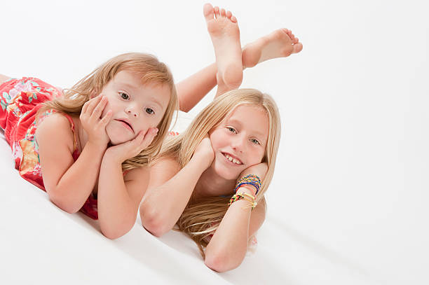 Teenage Girl and her sister Teenage Girl Lying on White Background with her sister. 13 14 years child teenage girls lying down stock pictures, royalty-free photos & images