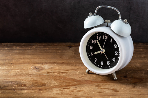 white alarm clock on wooden background