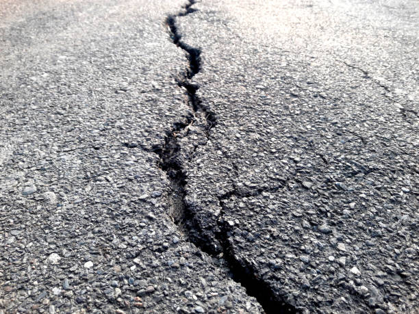 istock Cracked asphalt surface cracks. Post-earthquake damage. There were long, rough, winding cracks in the ground. Copy space. Texture background. Building maintenance and construction 1811031760