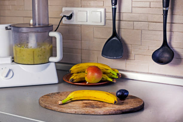 mashing bananas and apples in a food processor in the kitchen