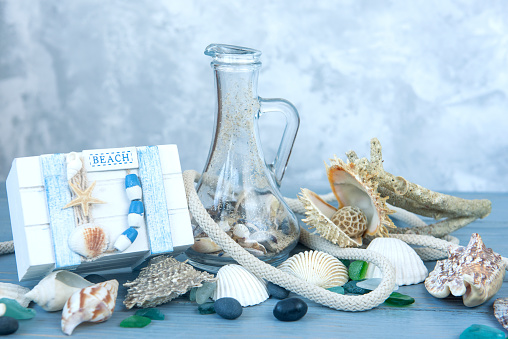 Marine decorative background made of shells and marine-themed details on a light blue wooden background.