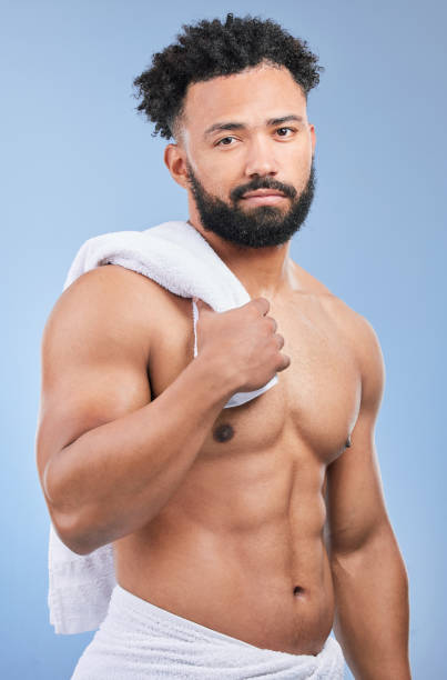 istock Shower towel, studio portrait and man confident in morning routine, body cleaning or self care maintenance. Bathroom skincare, grooming wash and model hygiene, beauty and dry skin on blue background 1811119607