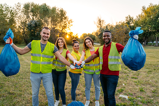 Portrait of a group of young nature conservation volunteers having a team handshake after cleaning up the garbage in the nature